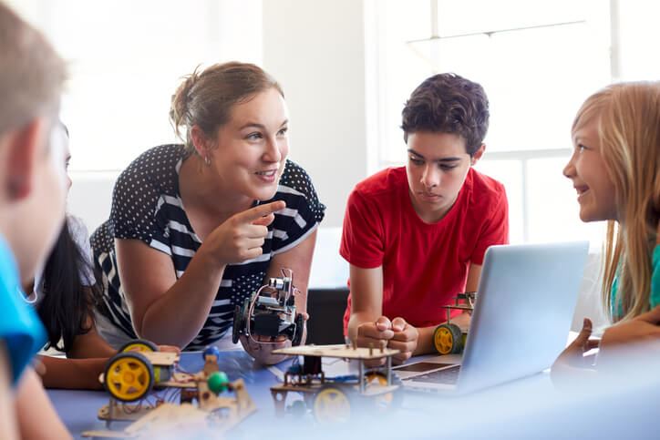 An education assistant training grad working on a robotics project with students