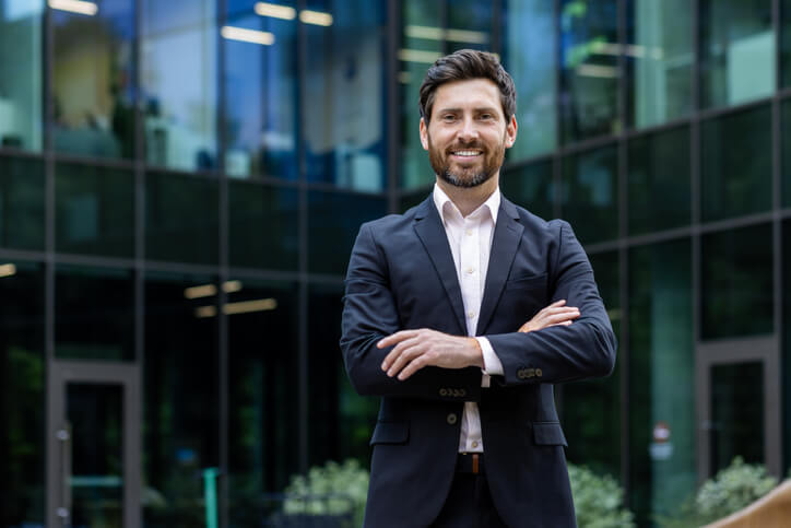 A smiling male businessman outside an office building after completing his international trade training