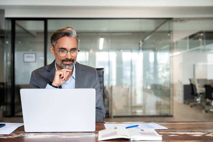  A focused male businessman working on a laptop after his international trade training