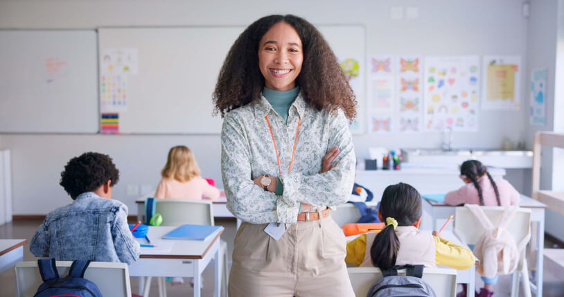 An education assistant training grad posing proudly in a classroom