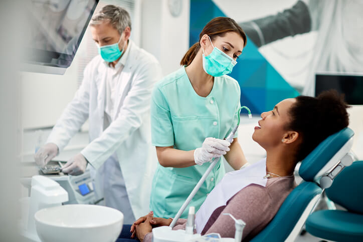 A dental assistant training grad helping the dentist with a procedure