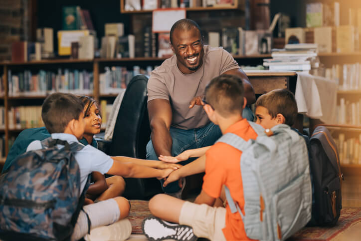 An education assistant training grad doing a handshake with students