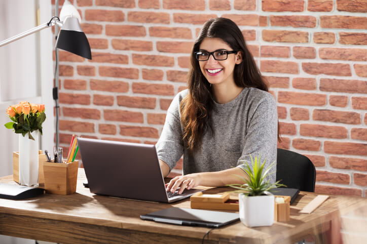 A smiling woman taking an online education assistant training course