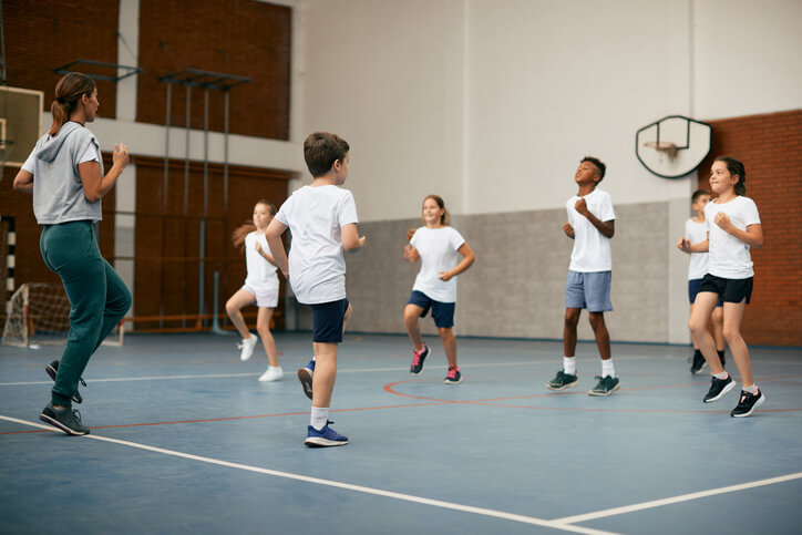 An active female education assistant engaging in sporting activities with her students