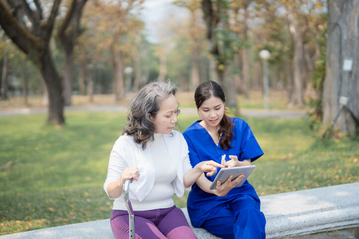 A healthcare assistant training grad helping a client use a tablet