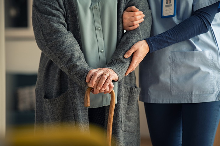 A healthcare assistant walking with a patient in hospital, completing her healthcare assistant training