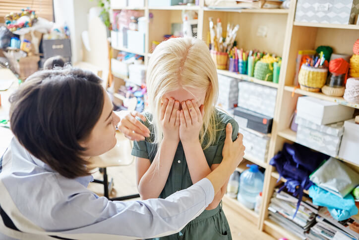 A caring education assistant supporting a student with mental health challenges in the classroom after completing her education assistant training.