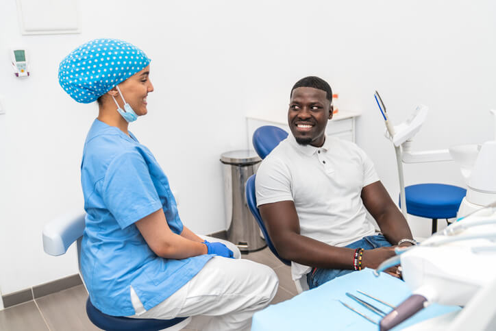 A smiling dental assistant talking to a patient chairside
