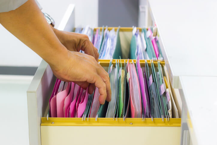 Medical office management training grad sorting through medical files