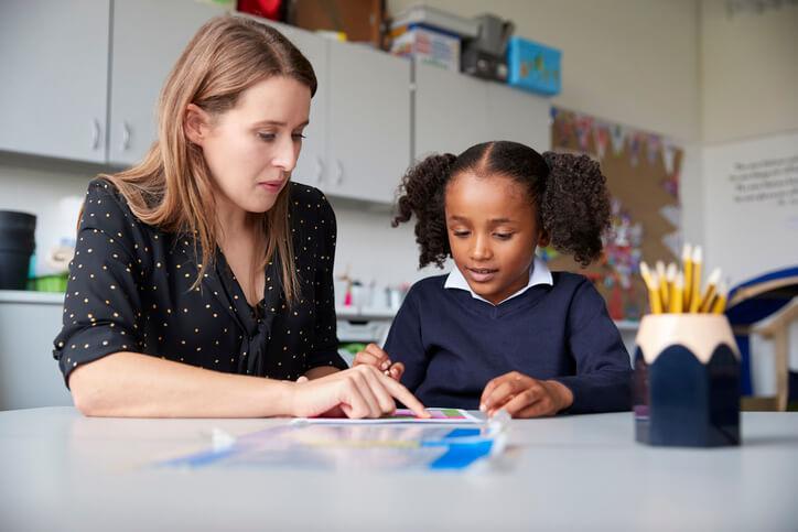 A trained education assistant assisting a pupil in an inclusive learning environment after her education assistant training
