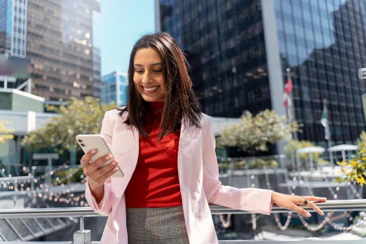 A career training grad using a mobile phone outside in a Canadian city