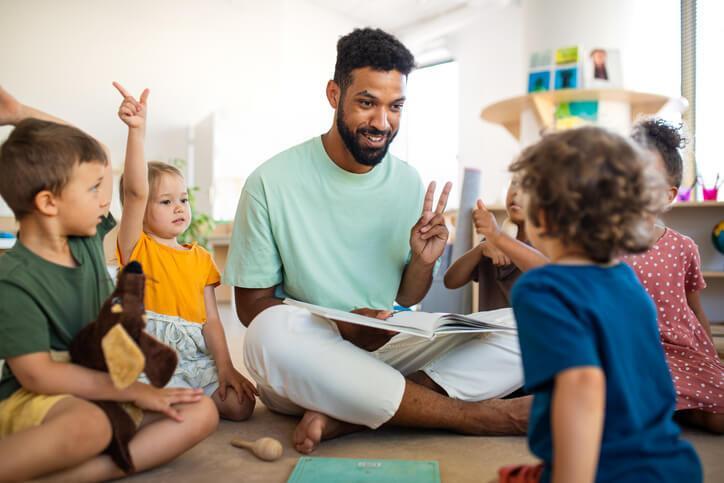 An education assistant helping a group of students with classroom activities after completing his education assistant training