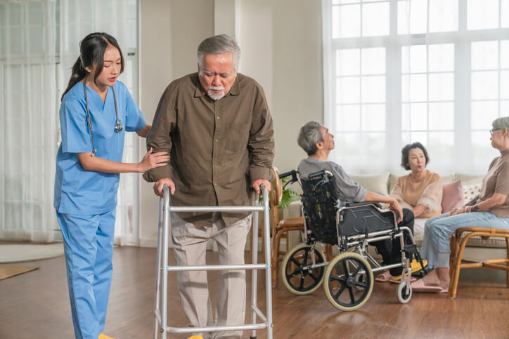 A health care assistant helping an elderly patient walk