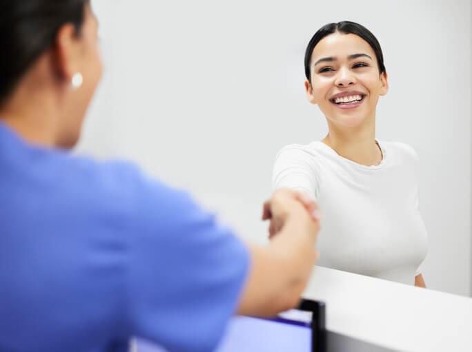 A dental reception course graduate greeting a patient at the front desk