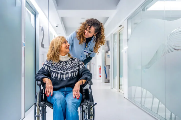 A health care aide helping a patient with mobility in a hospital setting