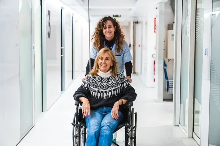 A health care assistant helping a patient with mobility in a hospital setting