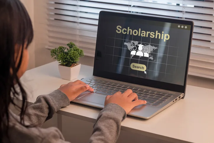 Student searching for scholarships on a laptop, representing funding options for education assistant training in BC.