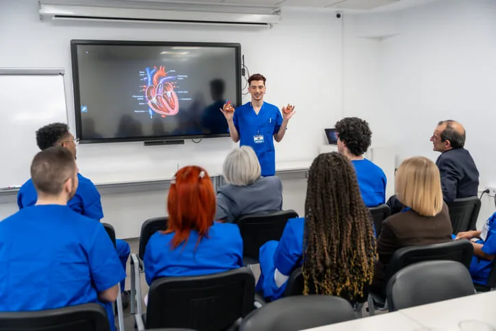 A practical nursing instructor guiding students in a classroom setting