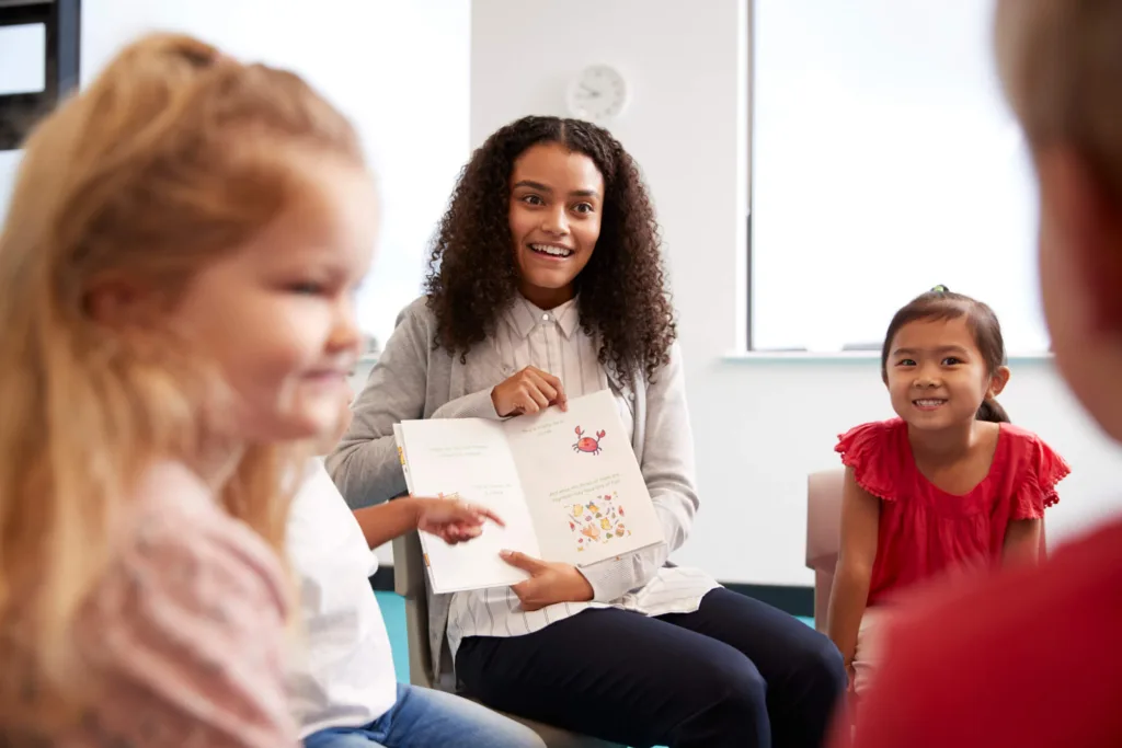 An Education Assistant student supporting a small reading group during practicum