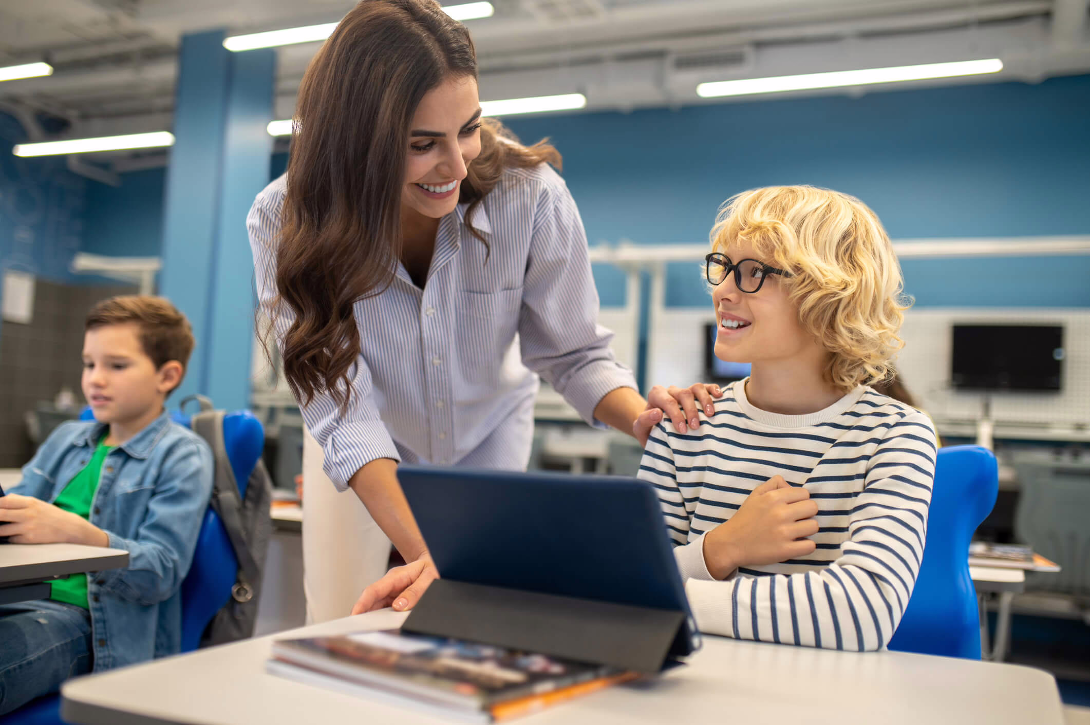 Education assistant helping a student use a tablet during a classroom learning activity